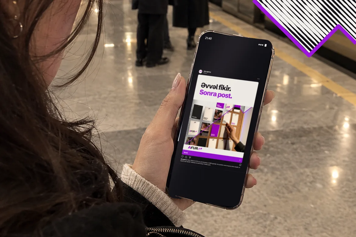 Bakı metrosunda qadın telefonda AFUR-un reklamına baxır: “Əvvəl fikir. Sonra post.” Qatarın qapıları açıqdır.